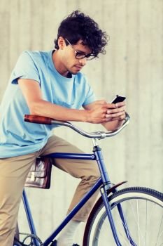 people, communication, technology, leisure and lifestyle - hipster man texting on smartphone with fixed gear bike on city street. man with smartphone and fixed gear bike on street