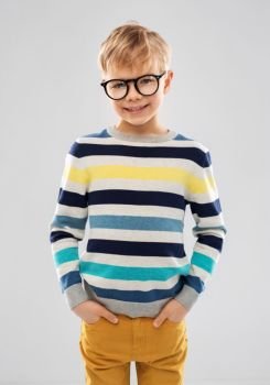 school, education and vision concept - portrait of smiling little boy in striped pullover and glasses over grey background. smiling boy in glasses and striped pullover