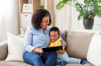 family, motherhood and technology concept - happy african american mother using tablet computer with little baby son at home. mother using tablet pc with baby son at home