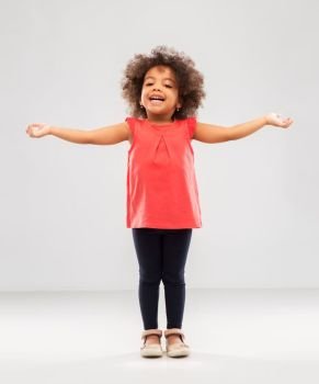 childhood and people concept - happy little african american girl with arms apart over grey background. happy little african american girl with arms apart