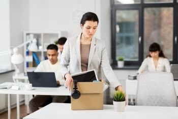 business, firing and job loss concept - sad fired female office worker packing her personal stuff and leaving. sad female office worker packing personal stuff