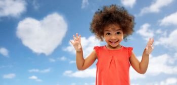 valentine’s day, childhood and people concept - happy little african american girl over blue sky and heart shaped cloud background. happy little african american girl over blue sky