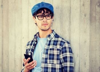people, music, technology, leisure and lifestyle - young hipster man with earphones and smartphone listening to music. man with earphones and smartphone listening music