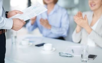 business, corporate and success concept - colleagues applauding to businessman with charts at office meeting or presentation. business team at office meeting or presentation