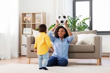 childhood, kids and people concept - happy african american mother and her baby son playing with soccer ball together on sofa at home. mother and baby playing with soccer ball at home