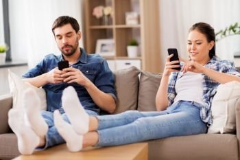 technology, internet addiction and people concept - couple with smartphones at home. couple with smartphones at home