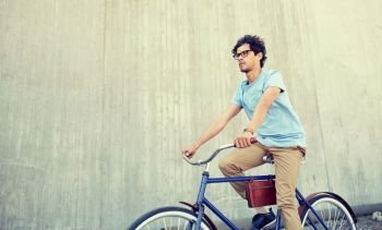 people, style, leisure and lifestyle - young hipster man riding fixed gear bike on city street. young hipster man riding fixed gear bike