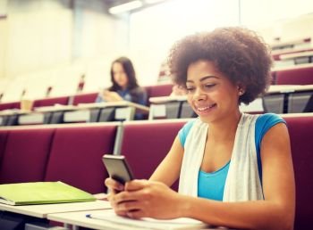 education, high school, university, learning and people concept - african student girl with smartphone at lecture. african student girl with smartphone at lecture