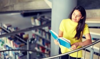 education, high school, university, learning and people concept - happy student girl reading book on stairs at library. high school student girl reading book at library