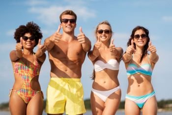 friendship, summer holidays and gesture concept - happy friends on beach showing thumbs up. happy friends showing thumbs up on summer beach