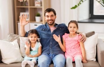 family, childhood and fatherhood concept - happy father with daughters waving hands at home. happy father with daughters waving hands at home