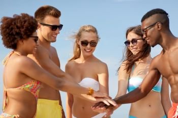 friendship, summer holidays and people concept - group of happy friends stacking hands together on beach. happy friends stacking hands on summer beach