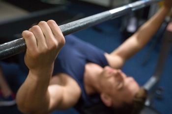sport, bodybuilding, lifestyle and people concept - close up of man or bodybuilder with barbell exercising in gym. close up of man with barbell exercising in gym