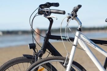 leisure, transport and sport concept - close up of two bicycles on beach. close up of two bicycles on beach
