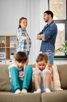 family problem, conflict and people concept - sad children closing ears while their parents quarreling at home. sad children and parents quarreling at home