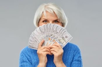 savings, finances and people concept - smiling senior woman hiding face behind hundreds of dollar money banknotes. senior woman with hundred dollar money banknotes