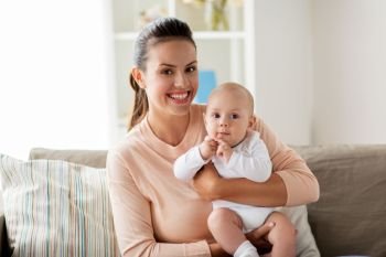 family, motherhood and people concept - happy mother with little baby boy sitting on sofa at home. happy mother with little baby boy at home