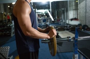 sport equipment, bodybuilding and people concept - close up of man or bodybuilder with barbell in gym. close up of man man with barbell in gym