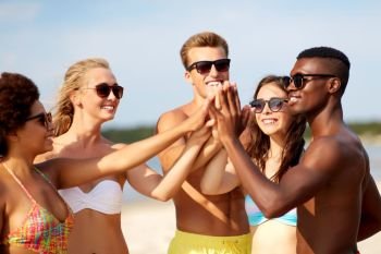friendship, summer holidays and people concept - group of happy friends making high five on beach. happy friends making high five on summer beach