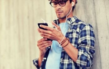 people, technology and lifestyle - close up of young hipster man with earphones and smartphone listening to music. man with earphones and smartphone listening music