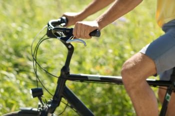 people, sport and lifestyle concept - close up of young man riding bicycle outdoors. close up of man riding bicycle outdoors