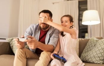 family, gaming and entertainment concept - happy father and little daughter with gamepads playing video game at home. father and daughter playing video game at home