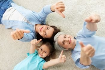 family, generation and female concept - mother, daughter and grandmother lying on floor and showing thumbs up from top. mother, daughter and grandmother showing thumbs up