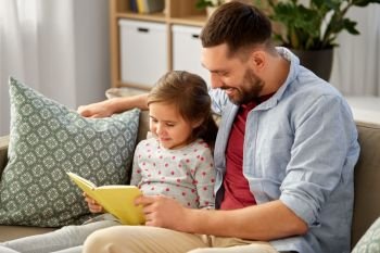 family, leisure and people concept - happy father and daughter reading book at home. happy father and daughter reading book at home