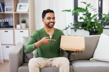 food delivery, consumption and people concept - smiling indian man with box of takeaway pizza at home. indian man with box of takeaway pizza at home