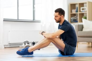 sport, technology and healthy lifestyle concept - man with fitness tracker exercising at home. man with fitness tracker exercising at home