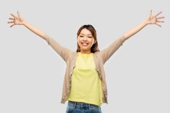 success, happiness and people concept - happy young asian woman over grey background. happy asian woman celebrating success