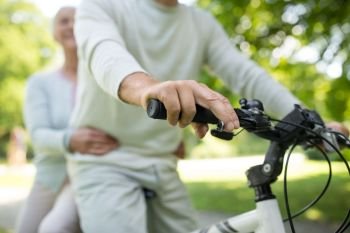 active old age, people and lifestyle concept - happy senior couple riding one bicycle together at summer park. happy senior couple riding one bicycle at park