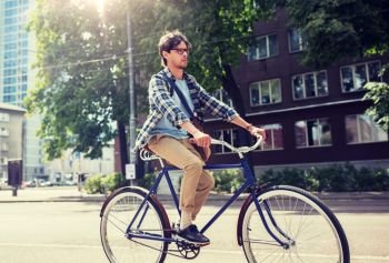 people, style, leisure and lifestyle - young hipster man with shoulder bag riding fixed gear bike on tallinn city street. young hipster man with bag riding fixed gear bike