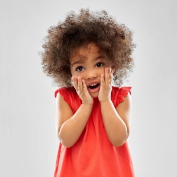 childhood and people concept - surprised or scared little african american girl with open mouth over grey background. surprised or scared little african american girl