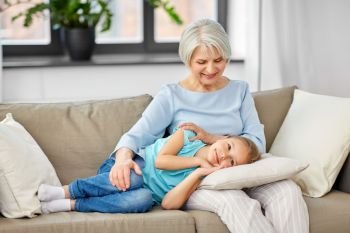 family, generation and people concept - happy smiling grandmother and granddaughter resting on pillow at home. grandmother and granddaughter resting on pillow
