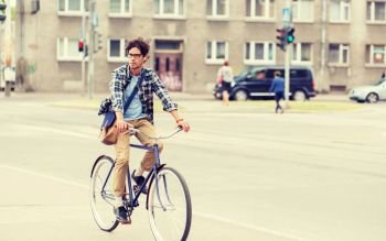 people, style, leisure and lifestyle - young hipster man with shoulder bag riding fixed gear bike on tallinn city street. young hipster man with bag riding fixed gear bike