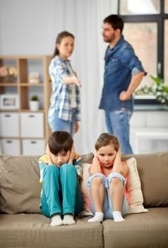 family problem, conflict and people concept - sad children closing ears while their parents quarreling at home. sad children and parents quarreling at home