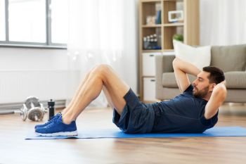 sport, fitness and healthy lifestyle concept - man making abdominal exercises at home. man making abdominal exercises at home