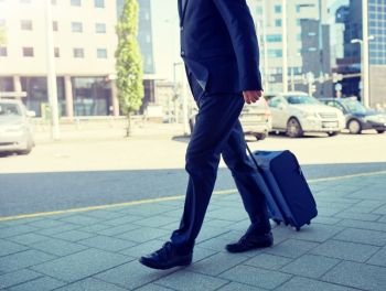 business trip and people concept - senior businessman walking with travel bag in city. senior businessman walking with travel bag in city