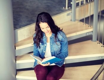 education, high school, university, learning and people concept - smiling student girl reading book sitting on stairs. high school student girl reading book on stairs
