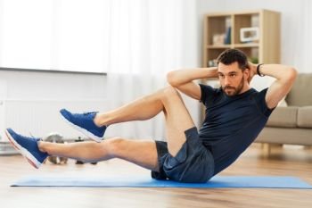 sport, fitness and healthy lifestyle concept - man making bicycle crunch on exercise mat and flexing abs at home. man making bicycle crunch exercise at home