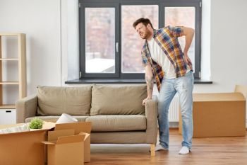 moving, people and real estate concept - man with sofa at new home suffering from back ache. man having back ache moving to new home