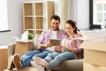 moving, people, repair and real estate concept - happy couple with photo frame and cardboard boxes sitting on sofa at new home. happy couple with boxes moving to new home
