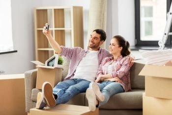 moving, repair and real estate concept - smiling couple taking selfie by smartphone at new home. couple taking selfie by smartphone at new home