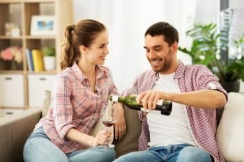 leisure, celebration and valentines day concept - happy couple drinking red wine at home. happy couple drinking red wine at home
