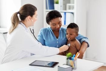 medicine, healthcare and pediatry concept - doctor with stethoscope listening to african american baby boy on medical exam at clinic. doctor with stethoscope listening baby at clinic