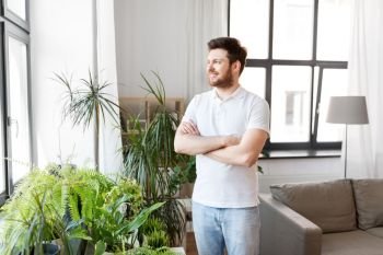 people, nature and plants concept - smiling man with houseplants at home. smiling man with houseplants at home