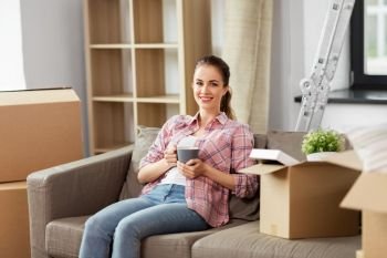 people, repair and real estate concept - smiling woman with stuff moving to new home and drinking coffee. woman moving to new home and drinking coffee