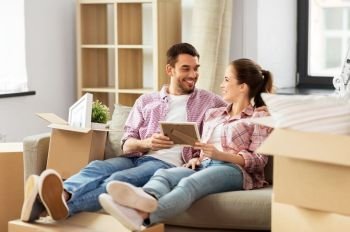 moving, people, repair and real estate concept - happy couple with photo frame and cardboard boxes sitting on sofa at new home. happy couple with boxes moving to new home