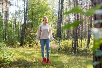season and leisure people concept - young woman with wicker basket and knife picking mushrooms in forest. woman with basket picking mushrooms in forest